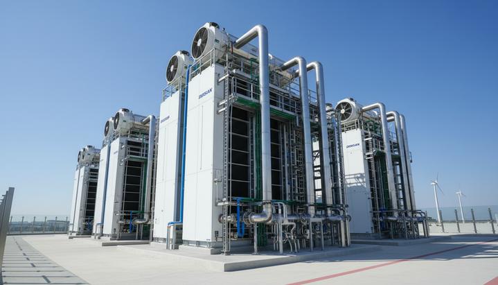 Современная водородная топливная электростанция Doosan с технологическими модулями и трубопроводами на фоне чистого неба.