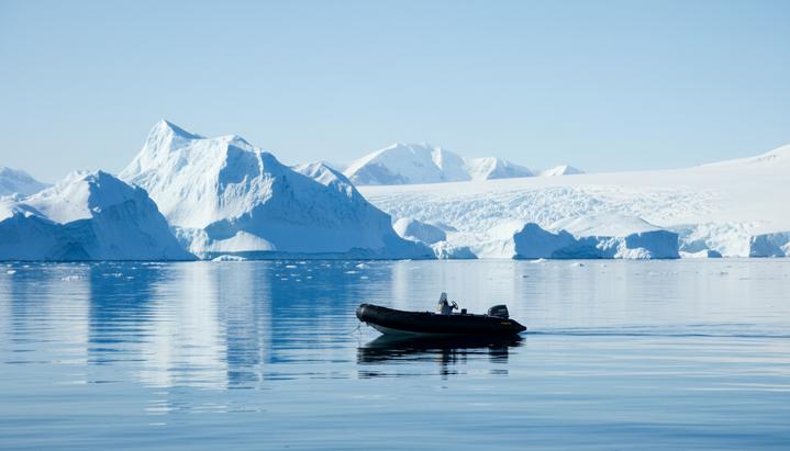 Надувная лодка Zodiac в спокойных водах Антарктиды на фоне величественных айсбергов и ледников.
